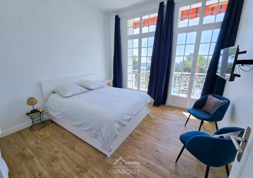 une chambre avec un lit et deux chaises et une fenêtre dans l'établissement Grand Standing Hyères T3 - Vue mer - Piscine - Tennis, à Hyères