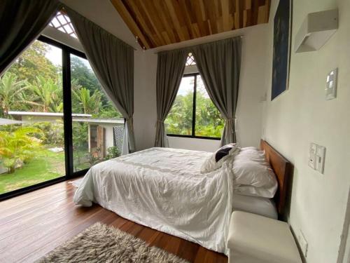 Schlafzimmer mit einem Bett und großen Fenstern in der Unterkunft Jungle Bungalow with Small Pool in Talamanca
