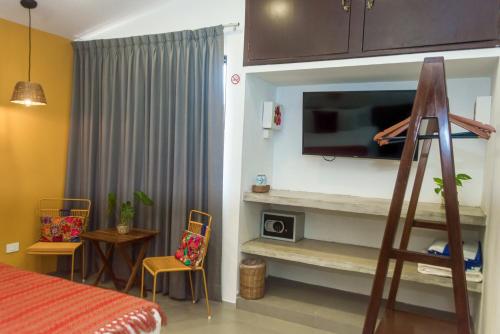 a room with a bed and a television on a wall at Hotel Boutique Casa Xaan in Valladolid