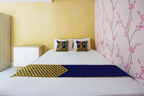 Un dormitorio con una cama blanca con almohadas azules y amarillas en OYO Life 93399 Kos Batulayar en Senggigi 