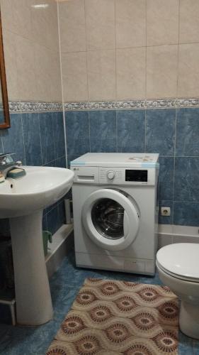 uma casa de banho com uma máquina de lavar roupa e um lavatório em Гостевой дом em Prigorodnoye