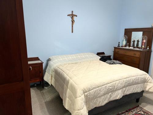 1 dormitorio con 1 cama y 1 cruz en la pared en Corte Magnano, en Ragalna
