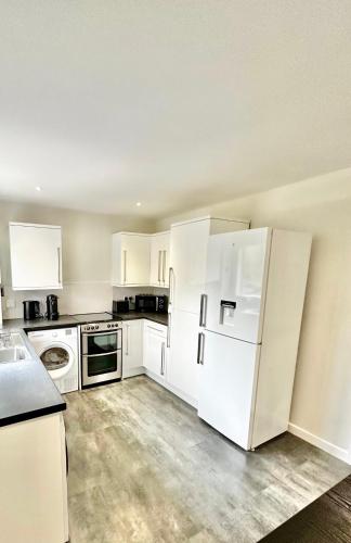 an empty kitchen with white cabinets and appliances at Convenient City House By Ankers Contractors Accommodation Manchester With Free Parking in Manchester