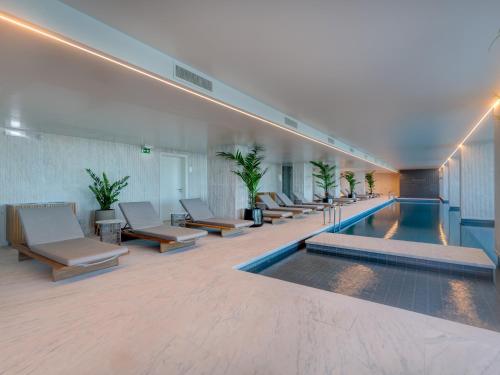 una piscina en un edificio con sillas y una piscina en Bayline - Beachfront Bliss & Spa by Bedzy, en Armação de Pêra