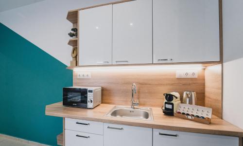 eine Küchentheke mit einer Spüle und einer Mikrowelle in der Unterkunft Szent Miklós Apartman -Keco- in Szeged
