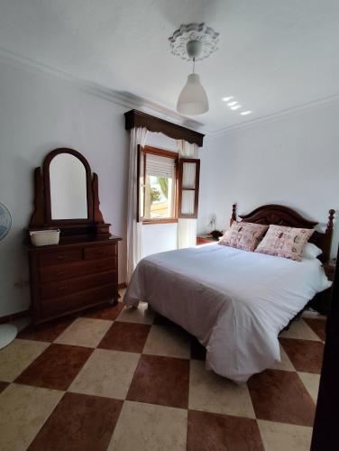 a bedroom with a bed and a dresser and a window at Casa Soledad in Vejer de la Frontera
