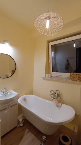 a bathroom with a white bath tub and a sink at Pink House Dziwnów 250 m od Morza in Dziwnów