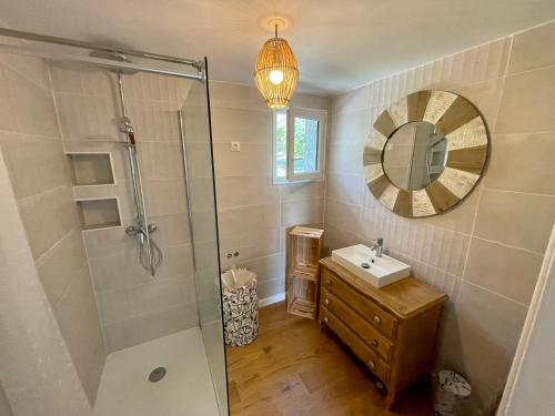 ein Bad mit einer Dusche, einem Waschbecken und einem Spiegel in der Unterkunft Villa au calme dans un domaine boisé in La Motte