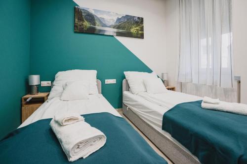 2 Betten in einem Zimmer mit grünen Wänden in der Unterkunft Szent Miklós Apartman -Keco- in Szeged