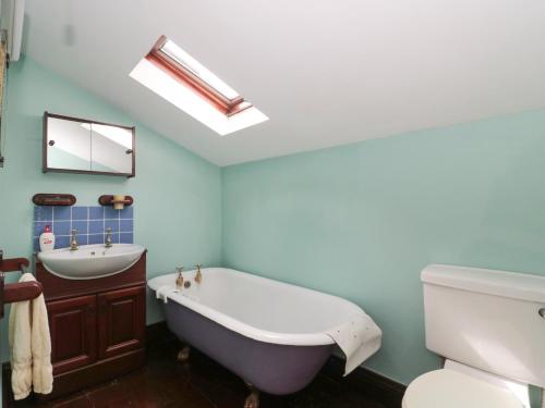 a bathroom with a white tub and a sink at Cathay House in Cheddar