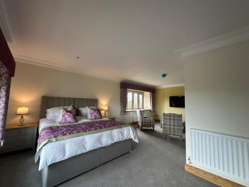 um quarto com uma cama grande e almofadas roxas em The Manor Boutique Hotel Restaurant and Bar em Conwy