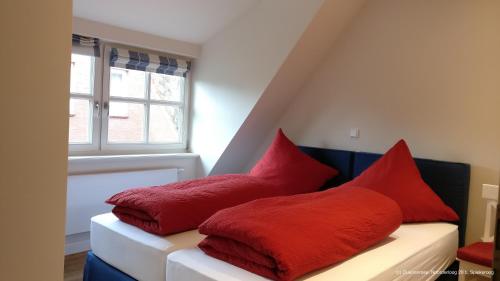 two red pillows sitting on a couch in a room at Dünenrose in Spiekeroog