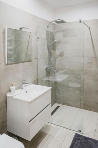 a white bathroom with a sink and a shower at Szent Miklós Apartman -Keco- in Szeged