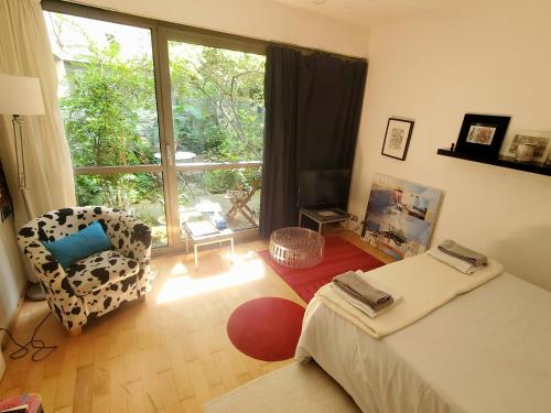 - une chambre avec un lit, une chaise et une fenêtre dans l'établissement Une chambre à Paris 20eme avec un petit jardin, à Paris