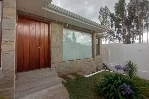 a house with a wooden door and a fence at Vive con nosotros tusvacaciones in Cuenca