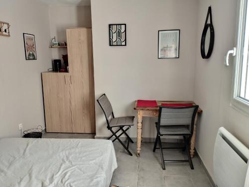 a bedroom with a table and two chairs and a bed at chambre avec un accès indépendant et salle de bain et toilette privatifs in Marquette-lès-Lille