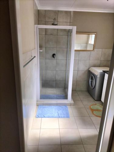 a shower with a glass door in a bathroom at GELET GUESTHOUSE in Roodepoort
