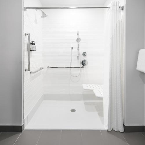 a white bathroom with a shower and a tub at Avid Hotels - Roseville - Minneapolis North, an IHG Hotel in Roseville