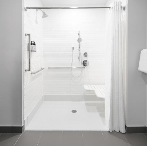 a white bathroom with a shower and a tub at Avid Hotels - Roseville - Minneapolis North by IHG in Roseville