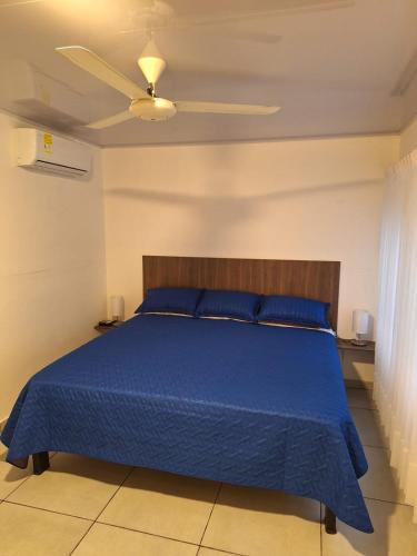 1 dormitorio con 1 cama azul y ventilador de techo en Casa Kalamary Crespo en Cartagena de Indias