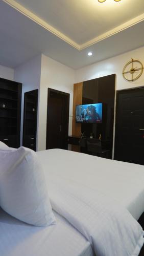a bedroom with a white bed and a flat screen tv at SHORTLETMART Apartments in Lekki