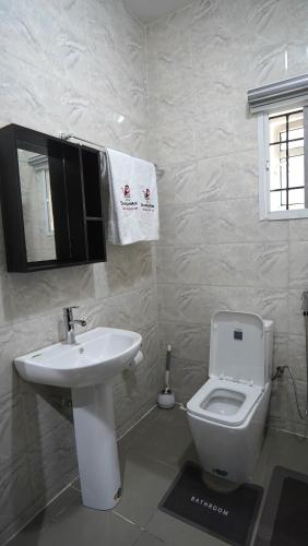 a bathroom with a white toilet and a sink at SHORTLETMART Guest House in Lekki