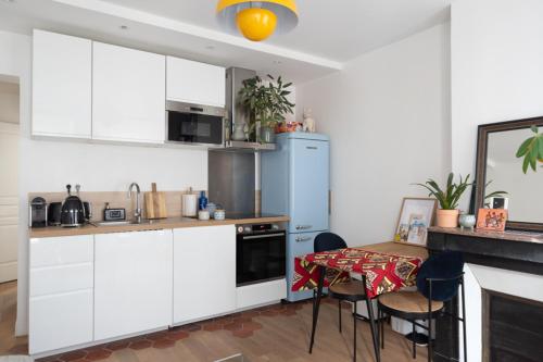 a kitchen with white cabinets and a table with chairs at Cozy 38 m near Père-Lachaise in Paris
