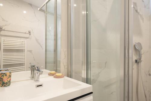y baño blanco con lavabo y ducha. en Cozy 38 m near Père-Lachaise en París