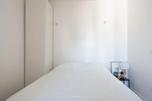 a white bed in a white room with a white wall at Cozy 38 m near Père-Lachaise in Paris