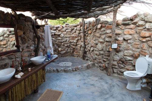 a stone bathroom with a toilet and a sink at Rumah Sudut in Siantan