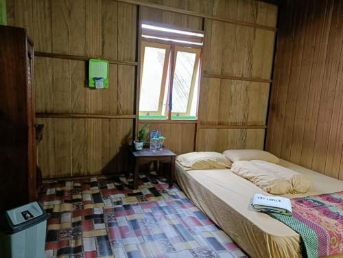 a bedroom with a bed and a window and a table at Rumah Sudut in Siantan