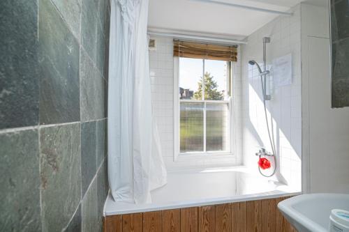 a bathroom with a bath tub and a window at Cozy House with Character & Garden. in London