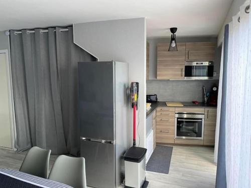 La cuisine est équipée d'un réfrigérateur et de quelques chaises. dans l'établissement Appartement T2 avec terrasses, à Le Castellas