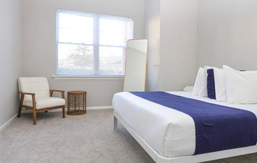 een slaapkamer met een bed, een stoel en een raam bij Comfortable Apartment with Pool Gym & other Amenities #4110 in Woburn