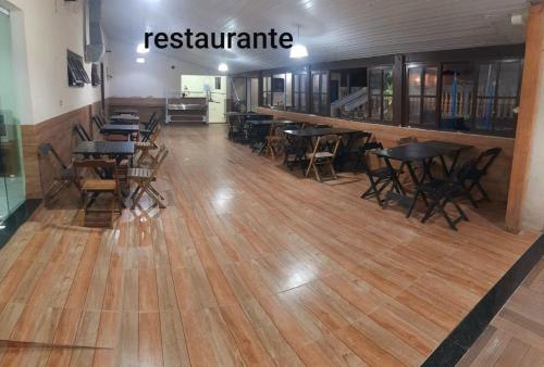 a restaurant with tables and chairs on a wooden floor at Flamboyant hostel in Cabo Frio