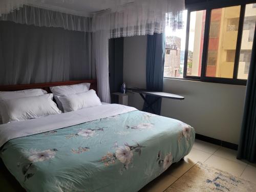 - une chambre avec un lit et une couverture bleue fleurie dans l'établissement Buildnet 59 Najjera 1, à Kampala
