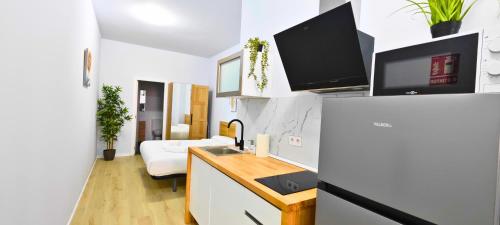cocina con escritorio y TV en la pared en Apartamentos Bulevar en Valencia