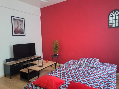 a living room with a red wall and a bed at Confortable Apart de 3 pièces in Poitiers