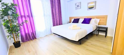 um quarto com uma cama branca e cortinas roxas em Apartamentos Bulevar em Valência