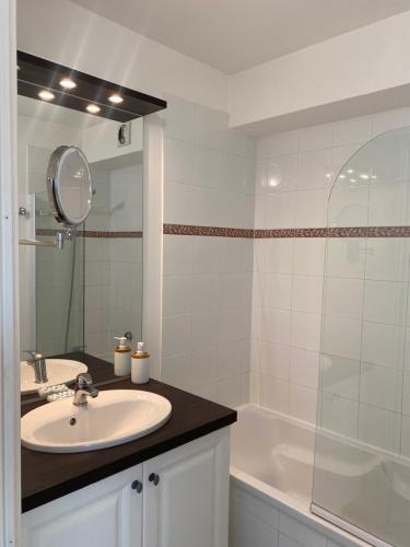ein Badezimmer mit einem Waschbecken, einer Badewanne und einem Spiegel in der Unterkunft Au pied des Alpilles in Paradou