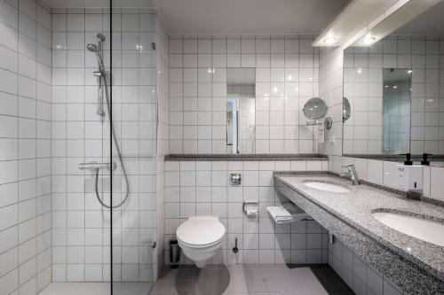 a bathroom with a toilet and two sinks and a shower at Scandic Opus Horsens in Horsens