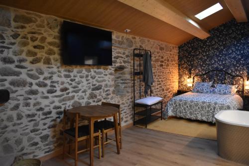 1 dormitorio con pared de piedra, cama y mesa en Cabana de Pili, en A Estrada
