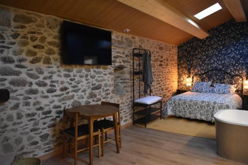 a bedroom with a stone wall with a bed and a table at Cabana de Pili in A Estrada