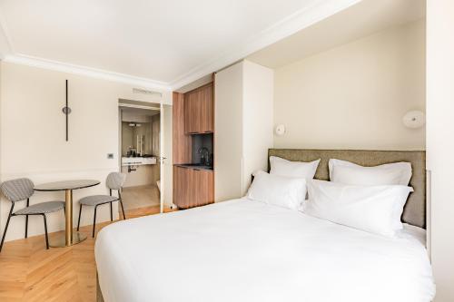 Un dormitorio con una gran cama blanca y una mesa en Maison du Moulin Vert, en París