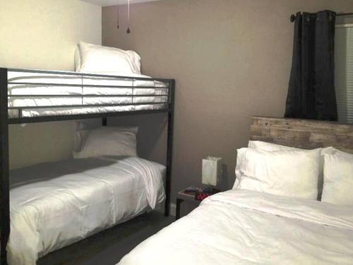 een slaapkamer met 2 stapelbedden met witte lakens bij 3BR 2 And A Half BA Cozy Quiet Home Away From Home in Port Arthur