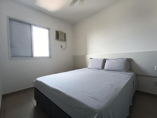 Schlafzimmer mit einem großen weißen Bett und einem Fenster in der Unterkunft Flat jardim Nova Aliança in Ribeirão Preto