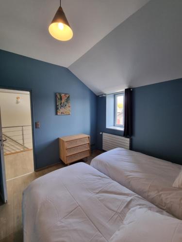 a bedroom with two beds and a blue wall at Le Coin Cosy in Saint-Valery-sur-Somme