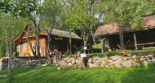 a log cabin with a stone wall in front of a house at Hidden Garden Kide (Chidea) in Cluj-Napoca