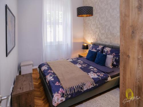 Un dormitorio con una cama con sábanas azules y una ventana. en Saint Moor Suite #1, en Pécs