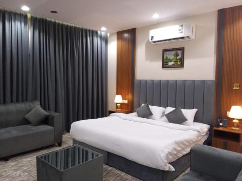 um quarto de hotel com uma cama e uma cadeira em فندق انسام طيبة للضيافة em Medina